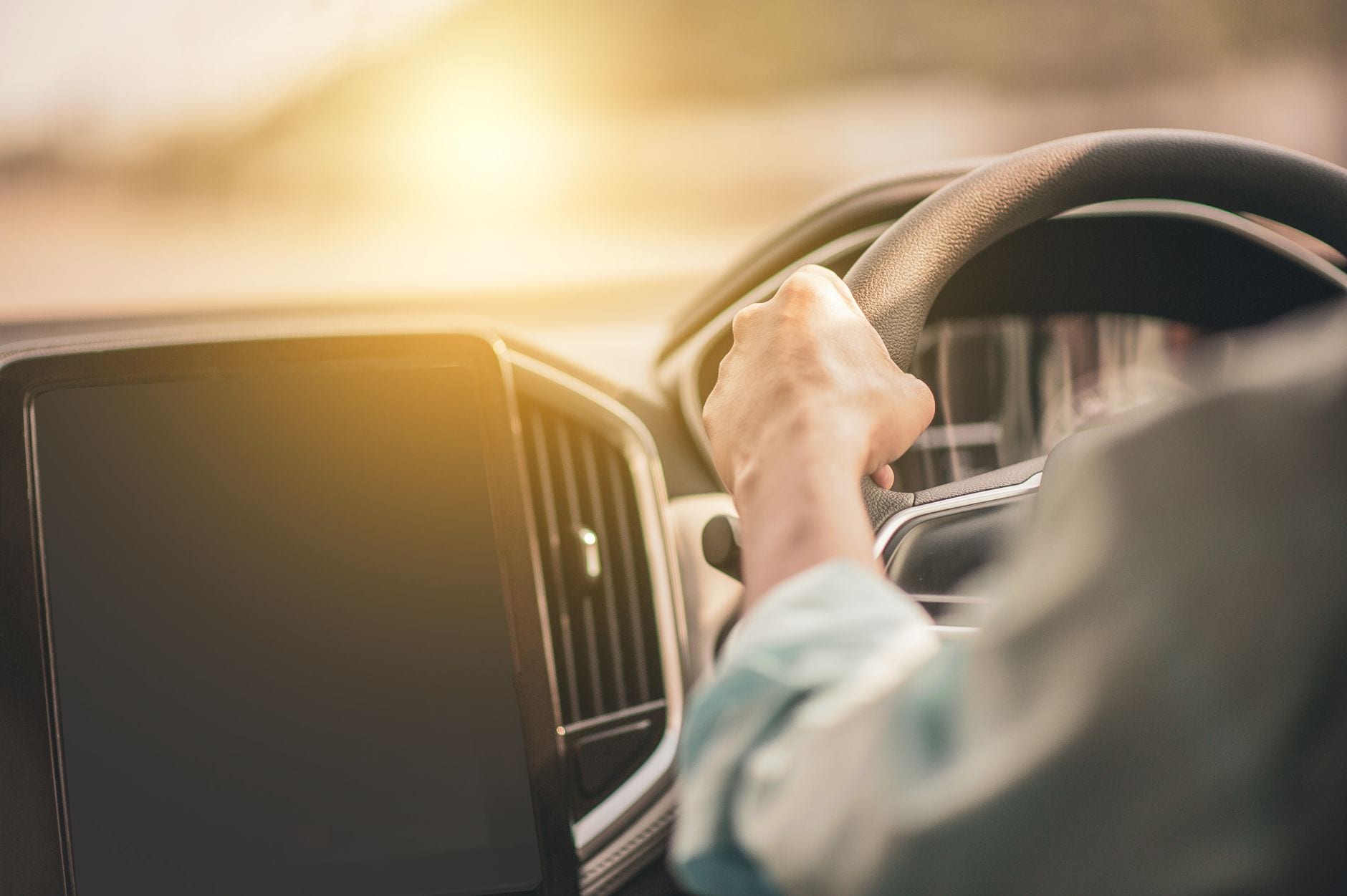 Hands on a steering wheel with sunlight through the window